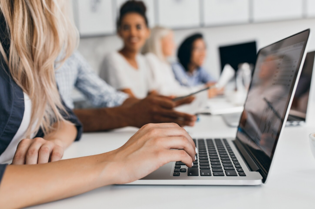view of a learner working on a laptop with some learners in the background